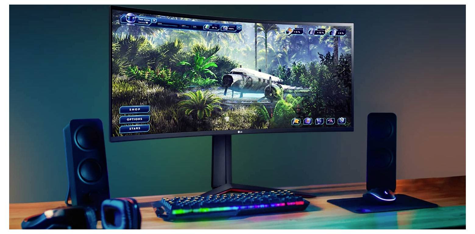 Ein Computermonitor zeigt ein lebendiges, immersives Videospiel in einer üppigen Dschungelumgebung. Eine Tastatur mit bunter Hintergrundbeleuchtung und Lautsprecher befinden sich auf dem Schreibtisch.