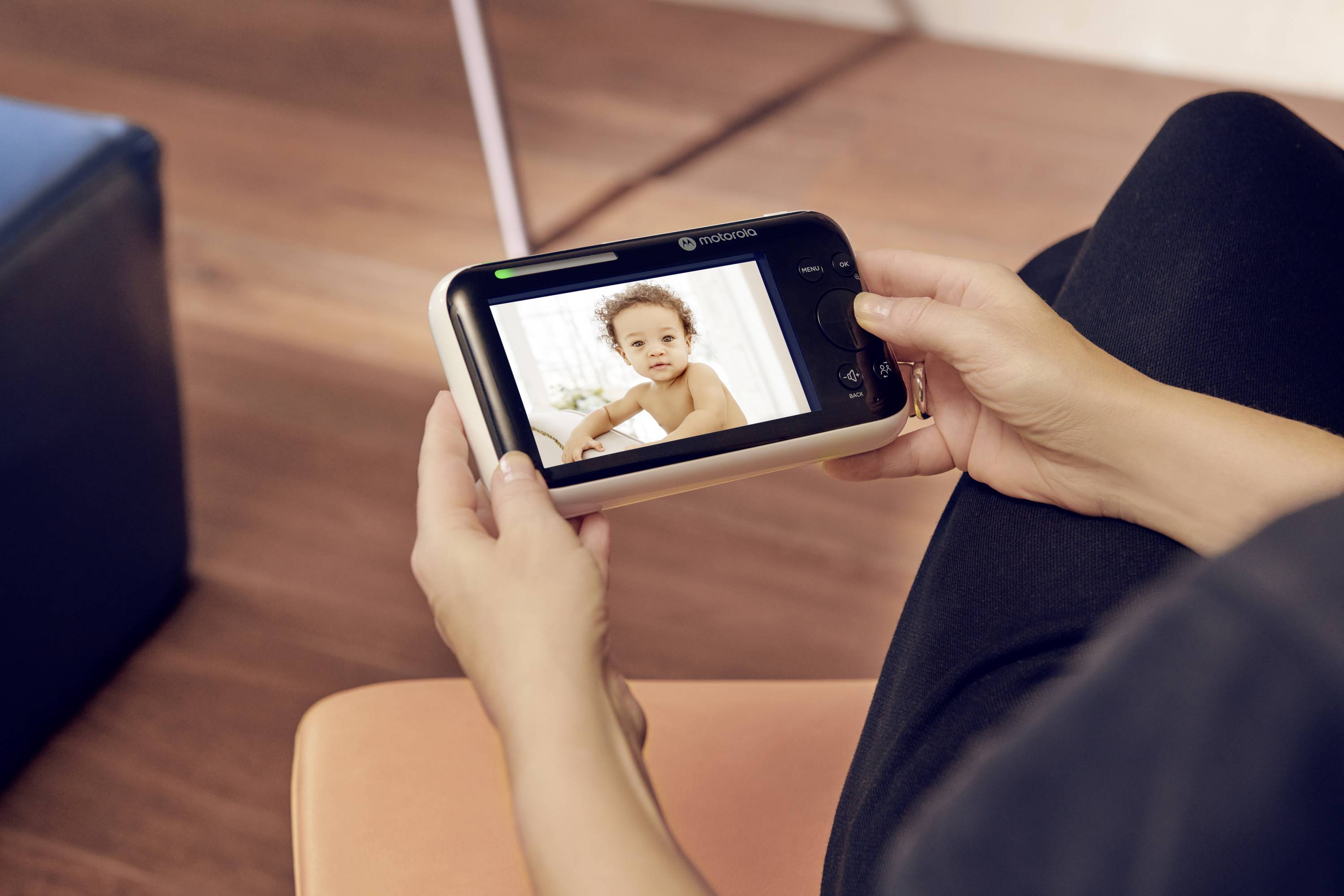 Eine Person hält einen Babyphone, auf dem ein Baby in die Kamera schaut.