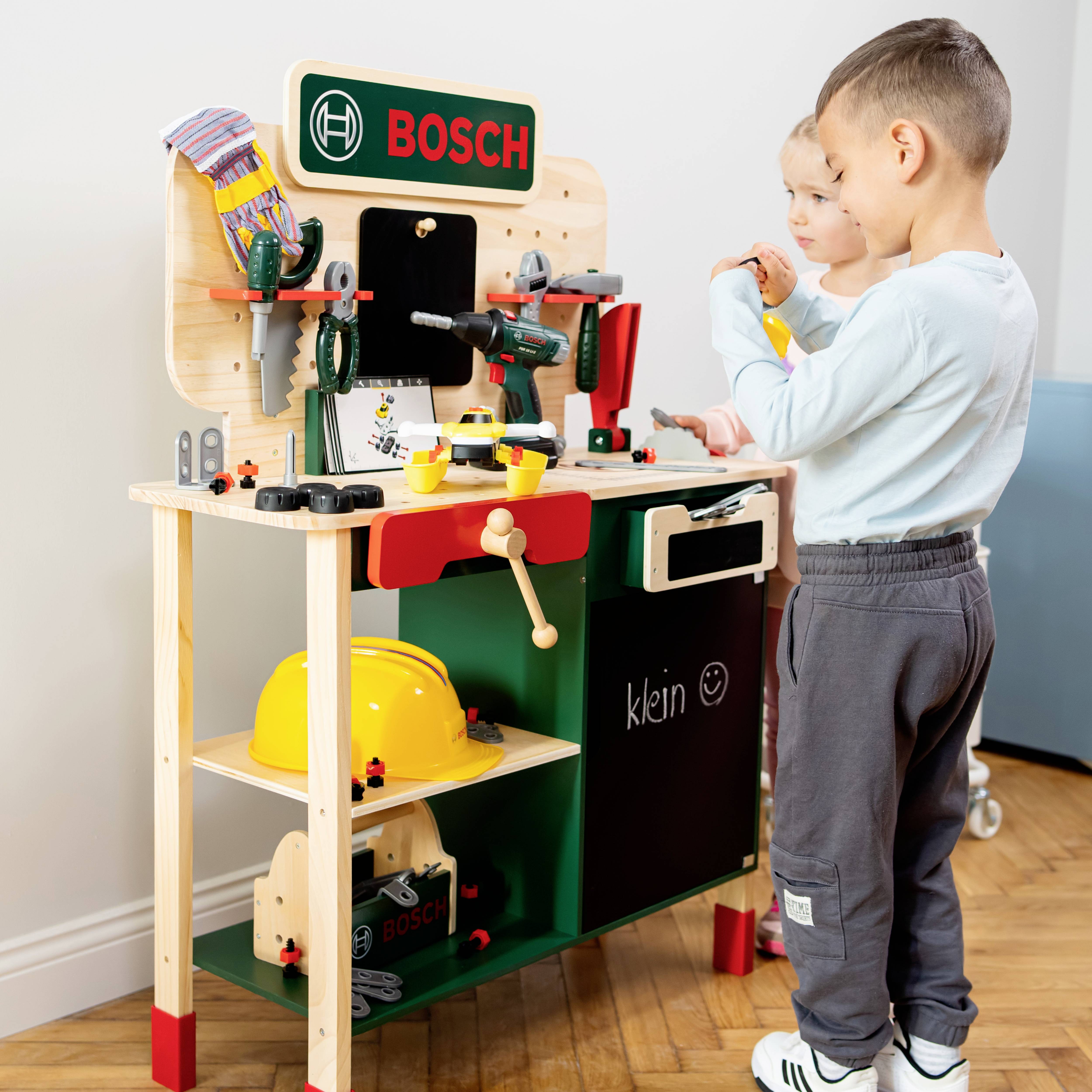 Kinder spielen mit einer Werkbank-Spielzeugset, das Werkzeuge und Zubehör mit der Marke 'Bosch' enthält.