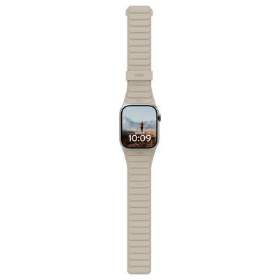 Eine Smartwatch mit einem beigen Band zeigt einen Bildschirm mit der Uhrzeit '10:09' und einem Hintergrundbild einer Person, die in einer Wüstenlandschaft steht.