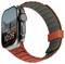 Eine Smartwatch mit einem rechteckigen Display, auf dem "Mon 5, 10:09" zu sehen ist und einem szenischen Bergpanorama im Hintergrund. Sie hat ein graues und rotes Gummiarmband.