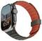 Smartwatch mit einem roten und schwarzen Armband, auf dem ein digitales Zifferblatt mit der Anzeige 'MON 5' und '10:09' zu sehen ist. Berglandschaft im Hintergrund.
