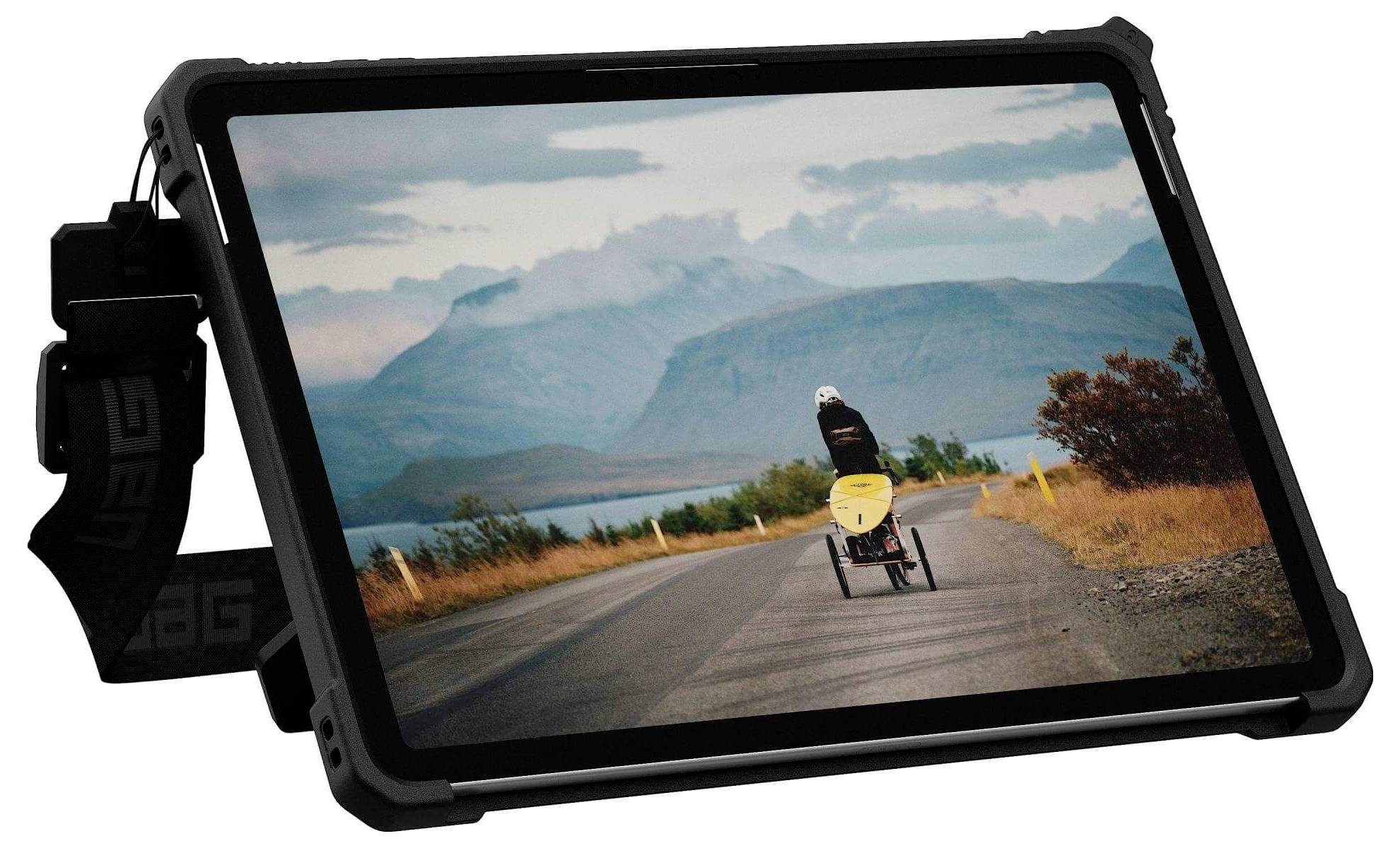 Ein Tablet zeigt ein Bild einer Person auf einem Liegerad, die eine Straße entlang fährt, mit Bergen in der Ferne unter einem bewölkten Himmel.