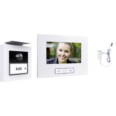 Videosprechanlage mit dem Gesicht einer Frau auf dem Bildschirm, wobei ein Namensschild und ein Wandadapter sichtbar sind.