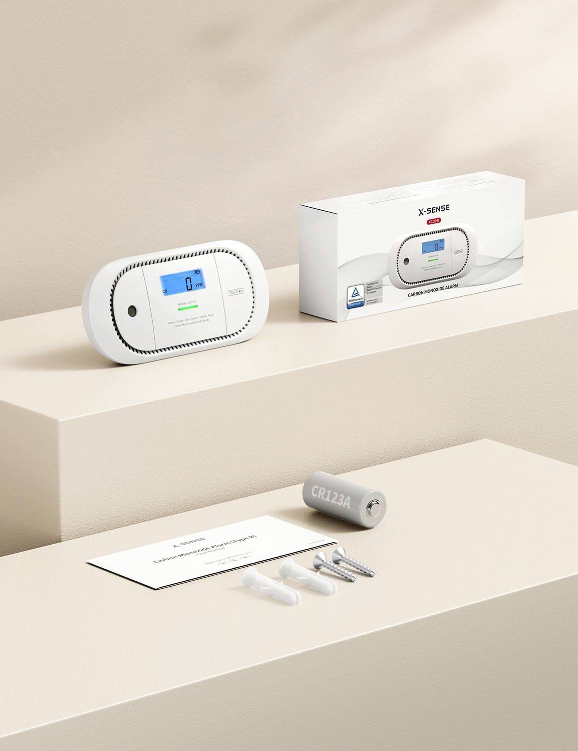 Kompakter Kohlenmonoxid-Detektor-Satz umfasst Hauptgerät mit digitaler Anzeige, Batterie, Schrauben und Bedienungsanleitung, vor einem beigen Hintergrund.