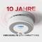 Ein Rauchmelder mit einem Schriftzug '10 Jahre' und 'Versiegelte Lithiumbatterie'. Ein digitales Display zeigt Informationen an.