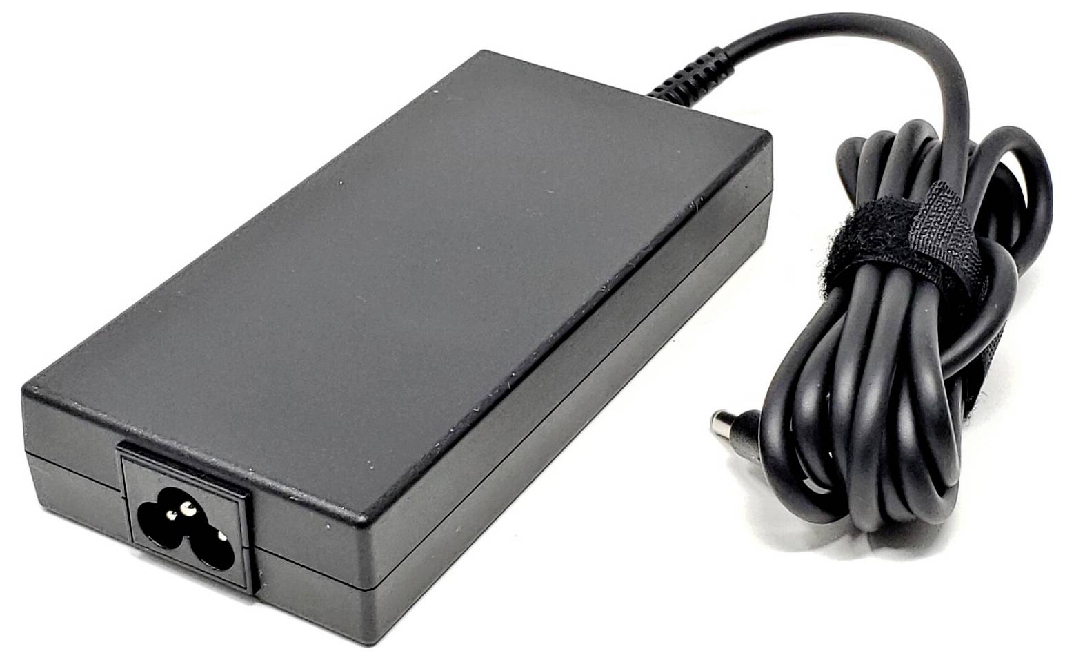 Schwarzes Netzteil mit Buchse, angeschlossen an ein spiralförmiges Kabel mit Stecker. Wird für elektronische Geräte verwendet.