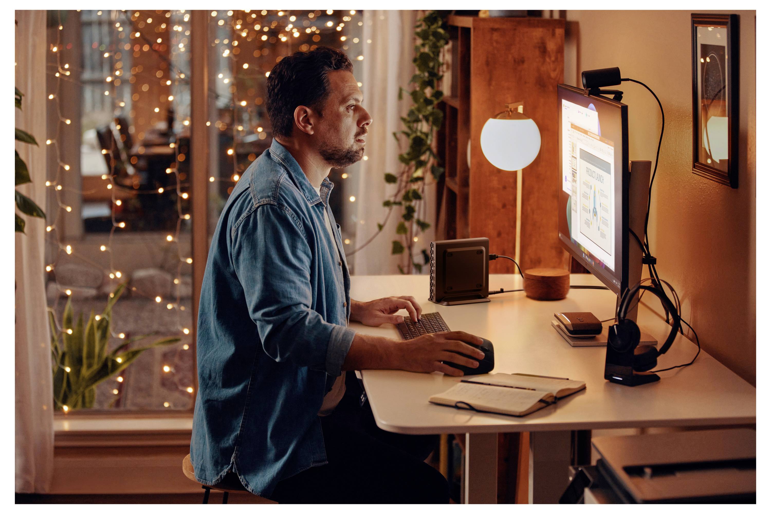 Eine Person, die an einem Schreibtisch mit einem Computer arbeitet, auf dem eine Datenvisualisierung zu sehen ist, umgeben von warmem Licht und dekorativen Lichterketten.