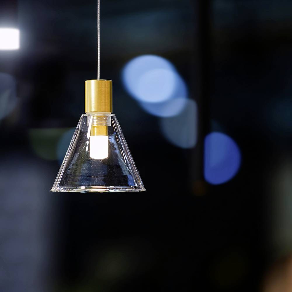 Eine hängende Pendelleuchte mit einem klaren Glasschirm leuchtet sanft vor einem dunklen, verschwommenen Hintergrund mit blauen kreisförmigen Bokeh-Highlights.