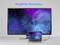 Ein großer Monitor zeigt eine sternengefüllte blaue und violette Galaxie mit dem Text '8K@60Hz Auflösung'; ein angeschlossener Laptop spiegelt das Bild wider.