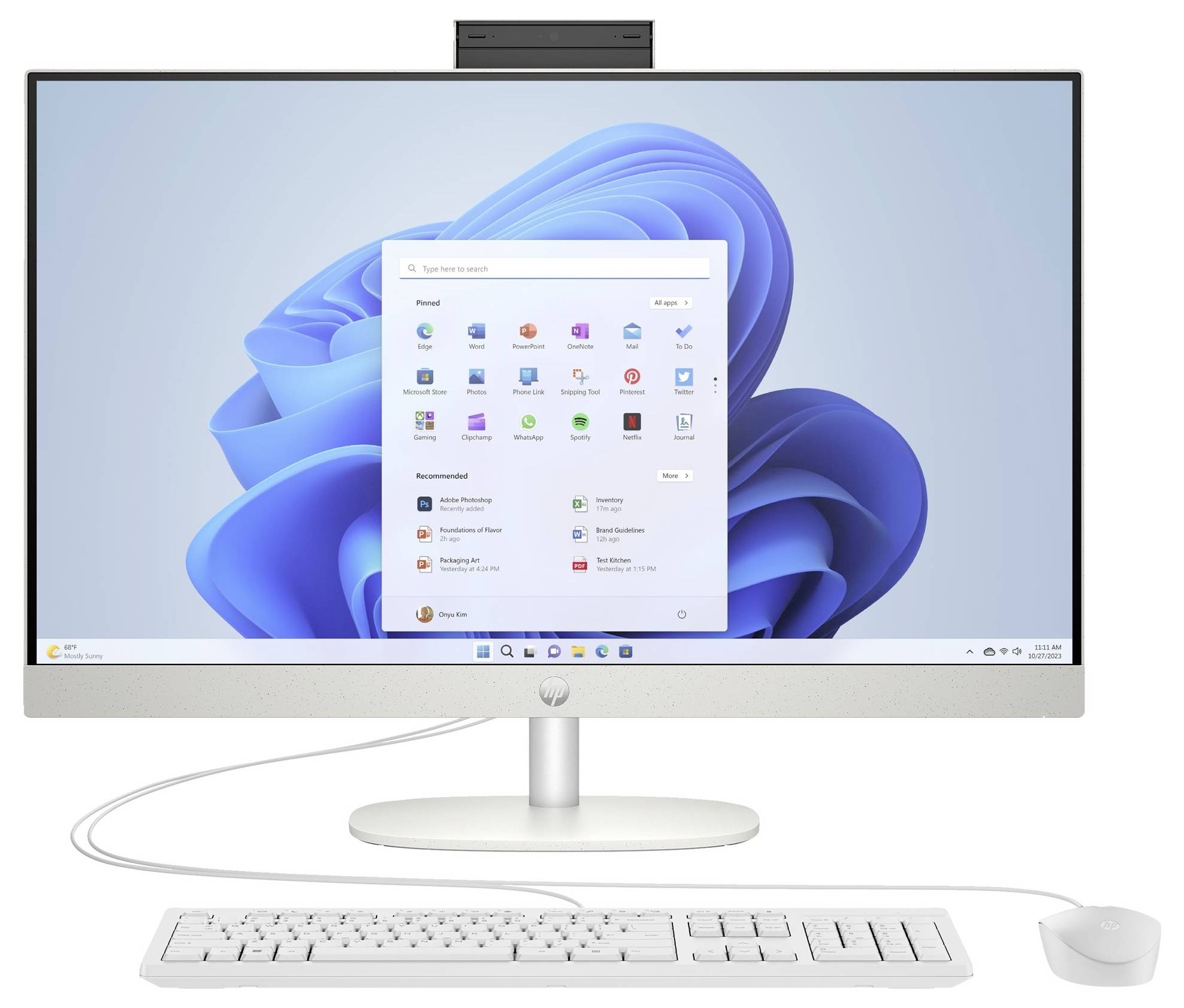 Ein Desktop-Computer mit einem großen Monitor, der den Windows 11-Startbildschirm anzeigt. Eine Tastatur und eine Maus sind unterhalb des Monitors angeschlossen.