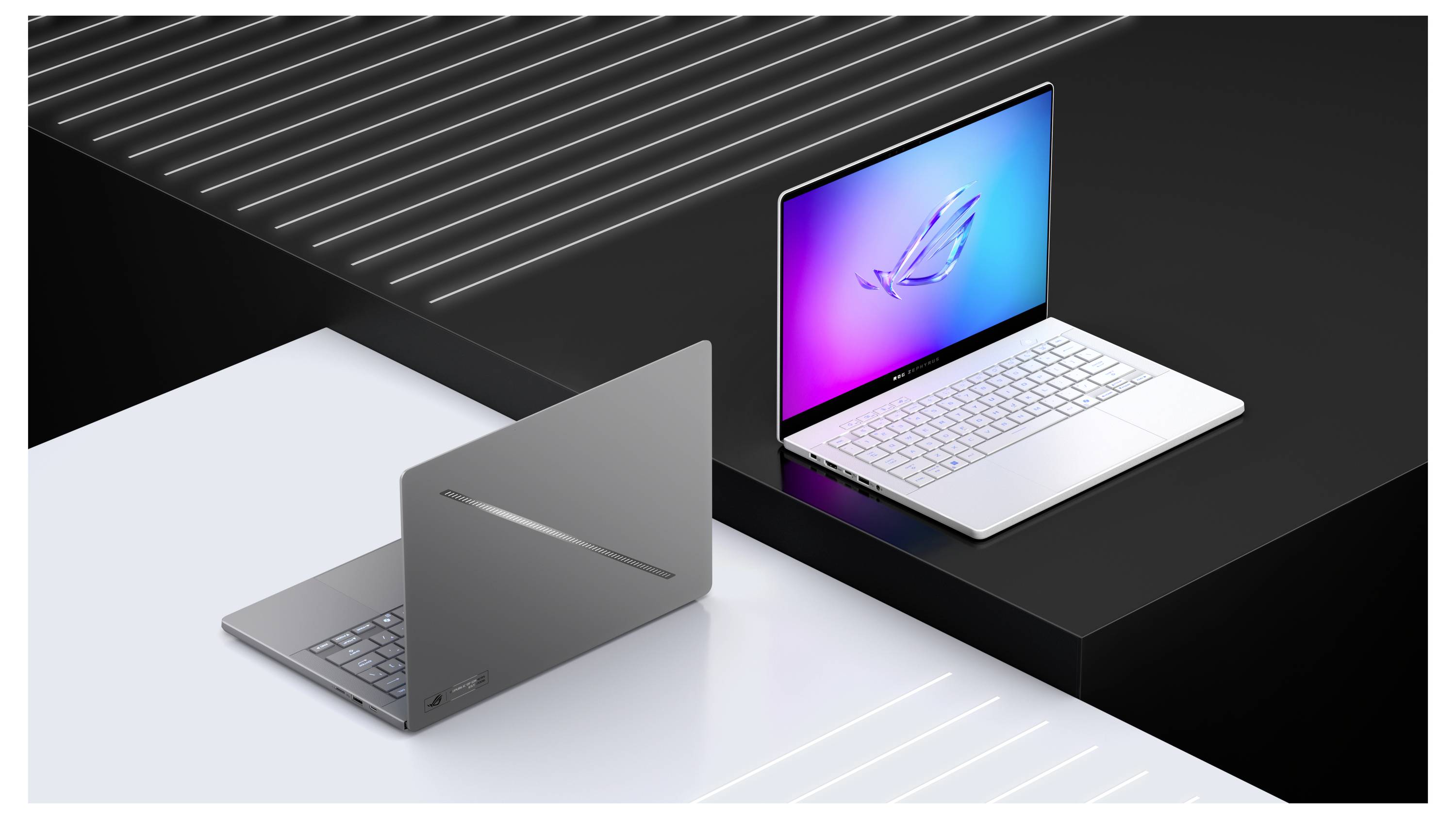 Elegante silberne und schwarze Laptops auf weißen und schwarzen Oberflächen, einer geöffnet mit einem bunten Bildschirm und einem stilisierten Logo, der andere geschlossen.