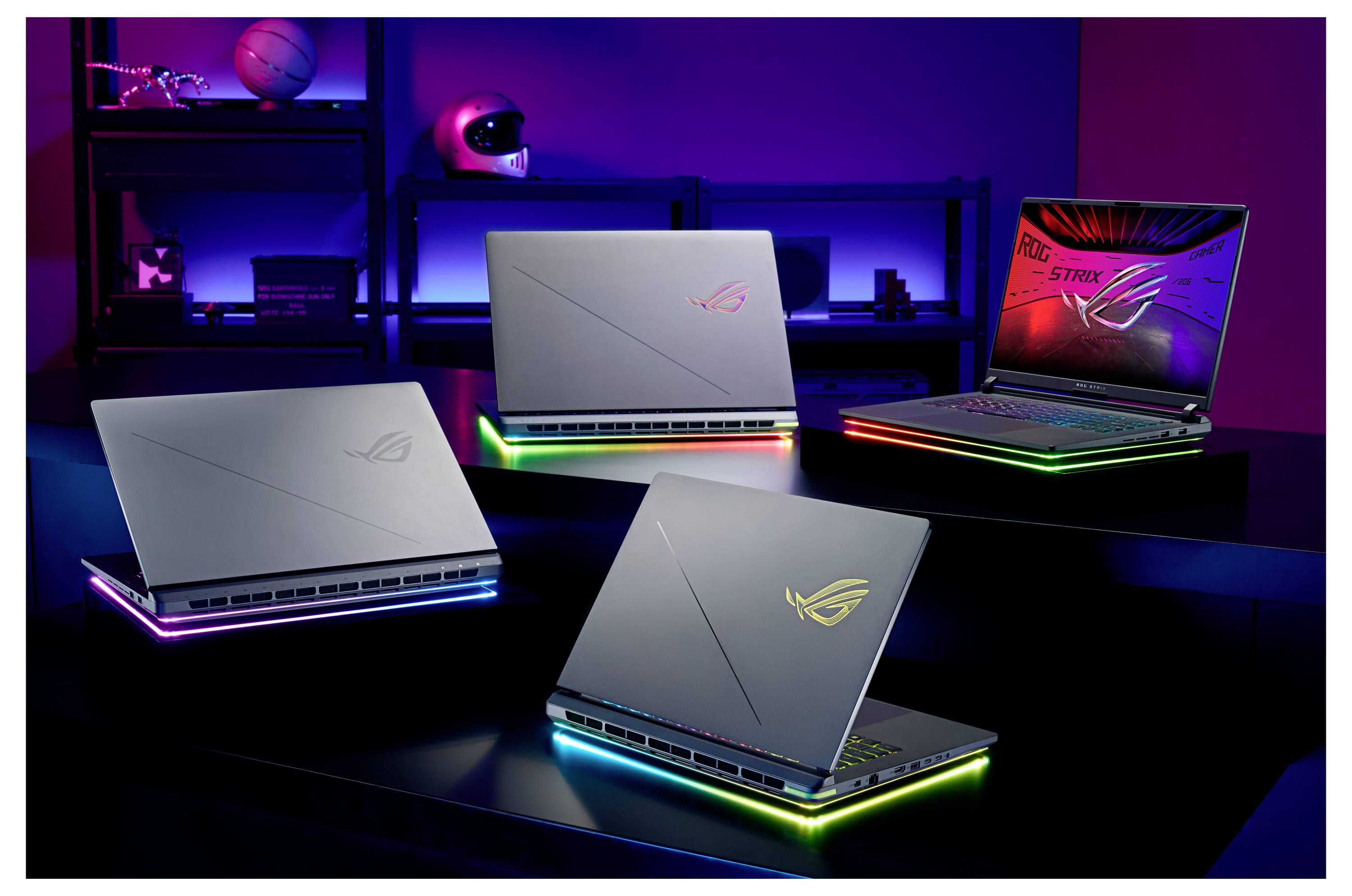 Laptops mit farbenfroher LED-Beleuchtung auf einem Tisch, die ihre hintergrundbeleuchteten Designs und futuristische Gaming-Ästhetik in einem düster beleuchteten Raum präsentieren.