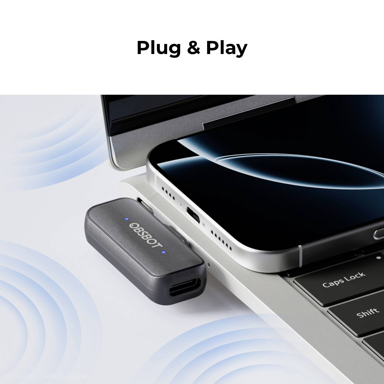 Ein Smartphone, das auf einer Laptop-Tastatur liegt, mit einem kleinen Gerät in der Nähe; der Text lautet "Plug & Play".