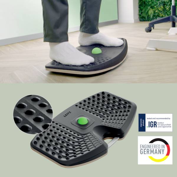 „Füße auf einer schwarzen ergonomischen Fußstütze mit strukturierter Oberfläche und Griff, daneben das Etikett „Entwickelt in Deutschland" neben der Qualitätszertifizierung."