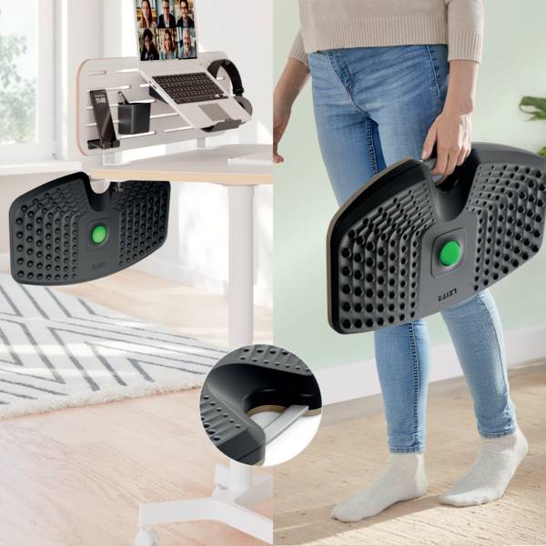 Ein Stehschreibtisch, auf dem ein Laptop, Telefone und ein Steh-Balancebrett zu sehen sind, mit teilweise sichtbarer Person, was eine Heimarbeitsplatz-Einrichtung andeutet.