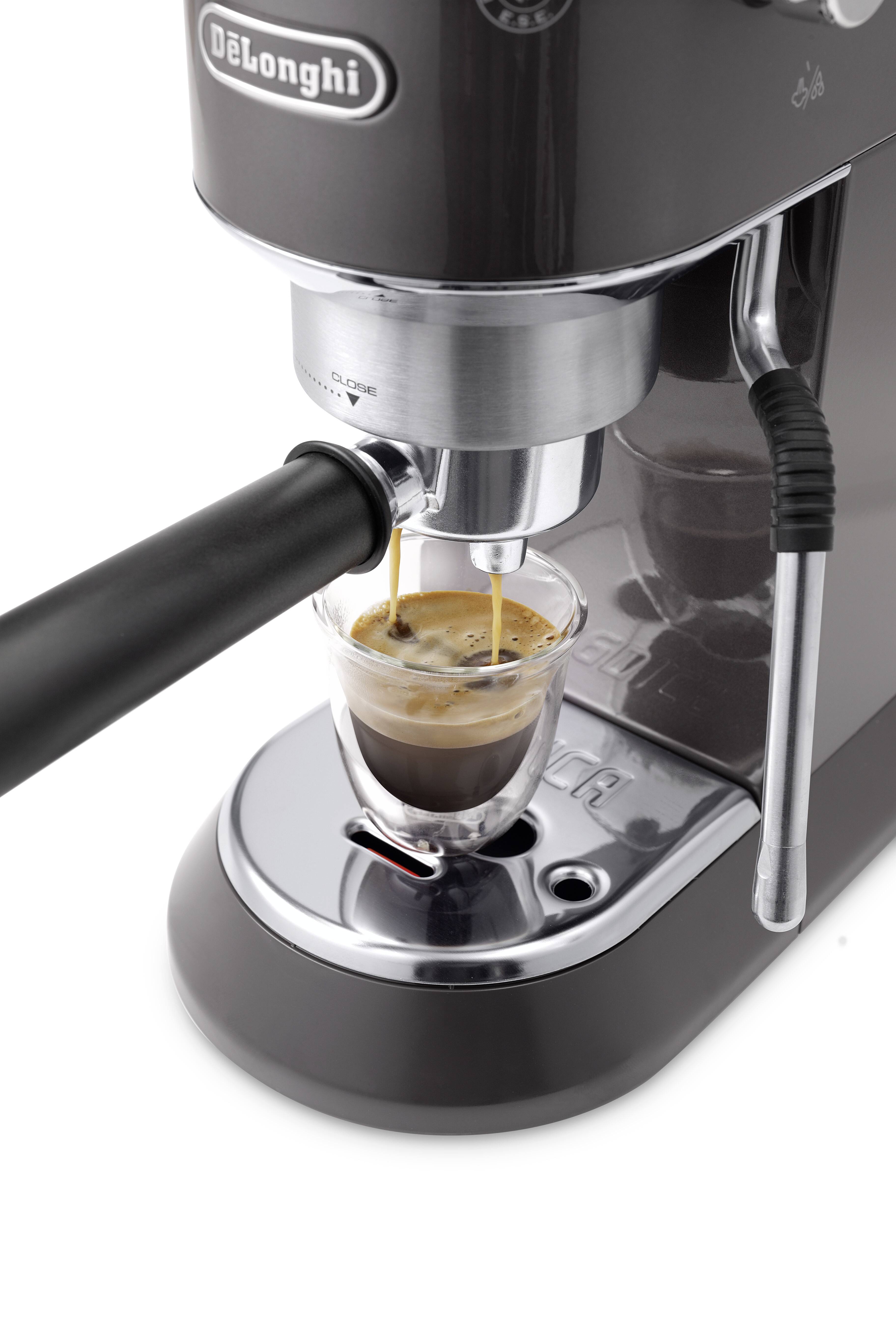 Kaffeemaschine, die einen Espresso in eine kleine Glasstasse einschenkt und dabei die Crema an der Oberfläche präsentiert. Metall- und schwarze Akzente unterstreichen ihr Design.