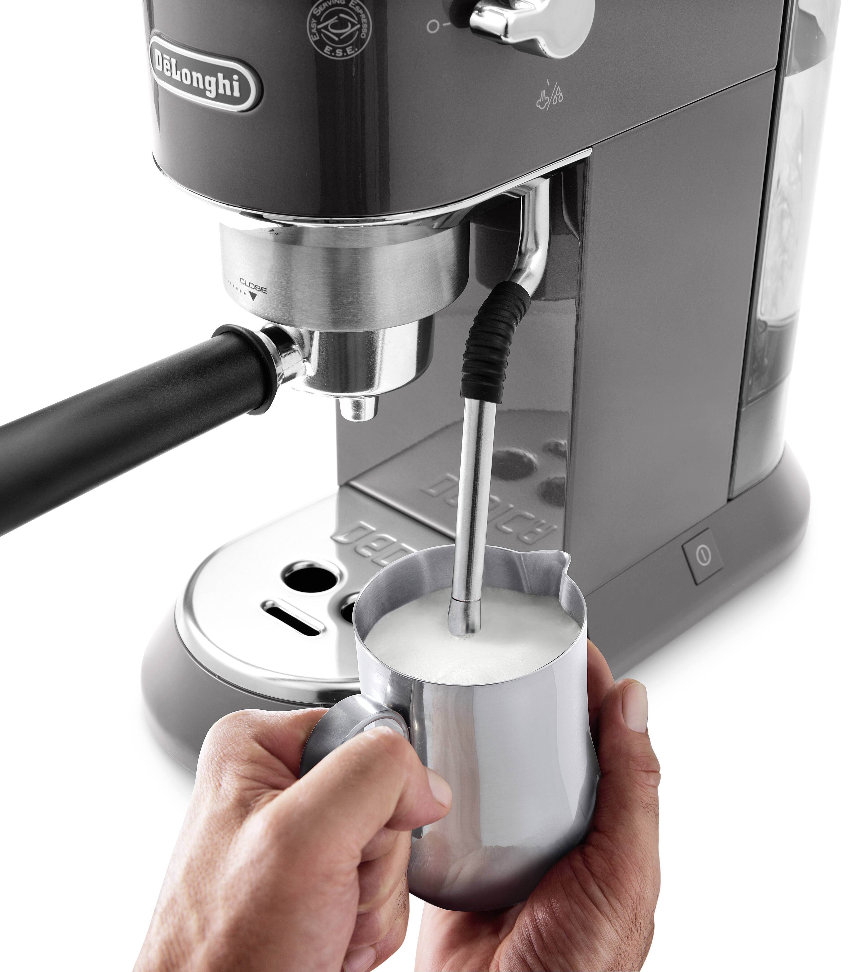 Eine Person verwendet eine DeLonghi-Espressomaschine, um Milch in einem Metallkrug zu dämpfen und den Aufschäumvorgang zu demonstrieren.