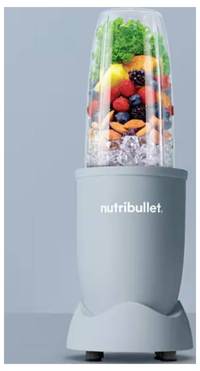 Ein grauer NutriBullet-Mixer, gefüllt mit frischem Obst, Gemüse und Eis vor einem hellblauen Hintergrund.