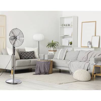 Ein modernes Wohnzimmer mit einem Standventilator, grauem Sofa, weißer Lampe und gemusterten Kissen. Ein gemütlicher, neutral getönter Raum mit einem Teppich.