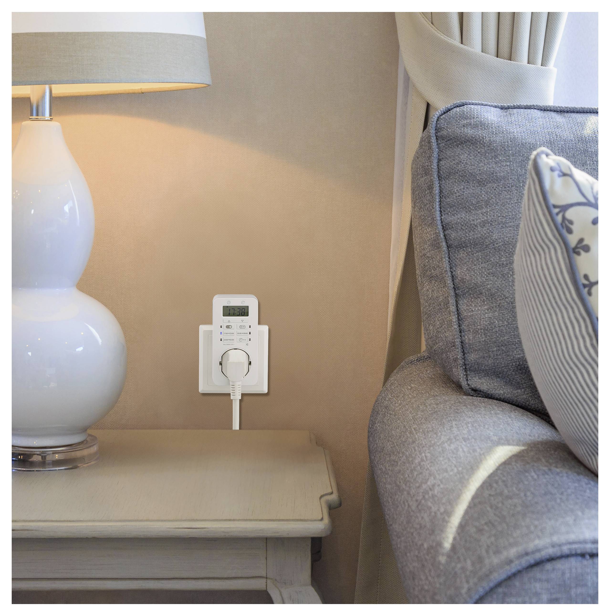 Ein digitaler Steckdosentimer ist an einer Steckdose neben einer Lampe und einem Sofa angeschlossen, was auf seine Verwendung für effizientes Energiemanagement im Haushalt hinweist.