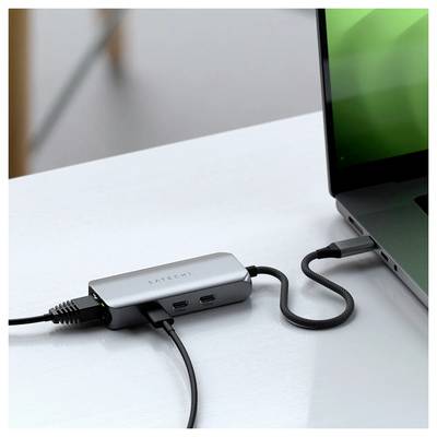 Ein Laptop, der an einen Mehrfachadapter mit mehreren Kabeln auf einem Schreibtisch angeschlossen ist.