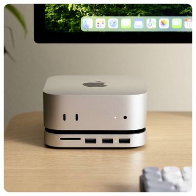 Silberner Desktop-Computer auf einem Schreibtisch, unter einem Monitor, der einen Waldlandschaftshintergrund zeigt. Das Gerät weist drei USB-Anschlüsse auf.