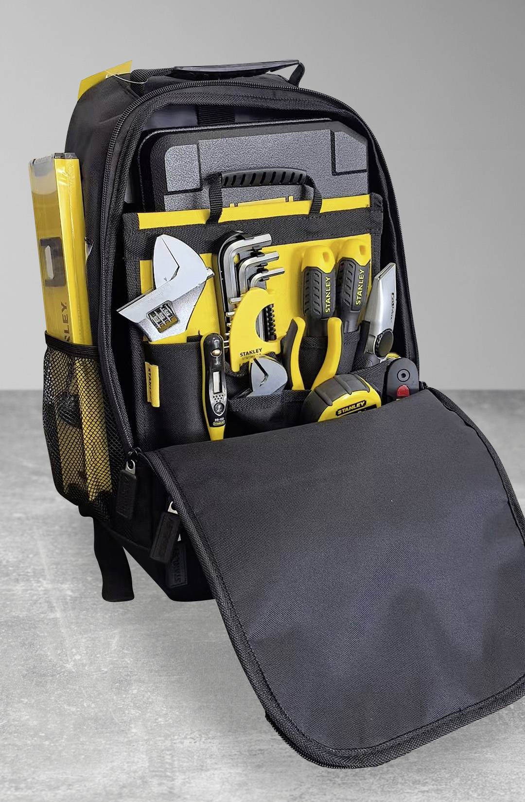 Schwarzer Rucksack mit offener Vorderseite, der einen organisierten Satz gelber und silberner Handwerkzeuge zeigt, einschließlich Schraubenschlüssel, Zangen und einer Wasserwaage.