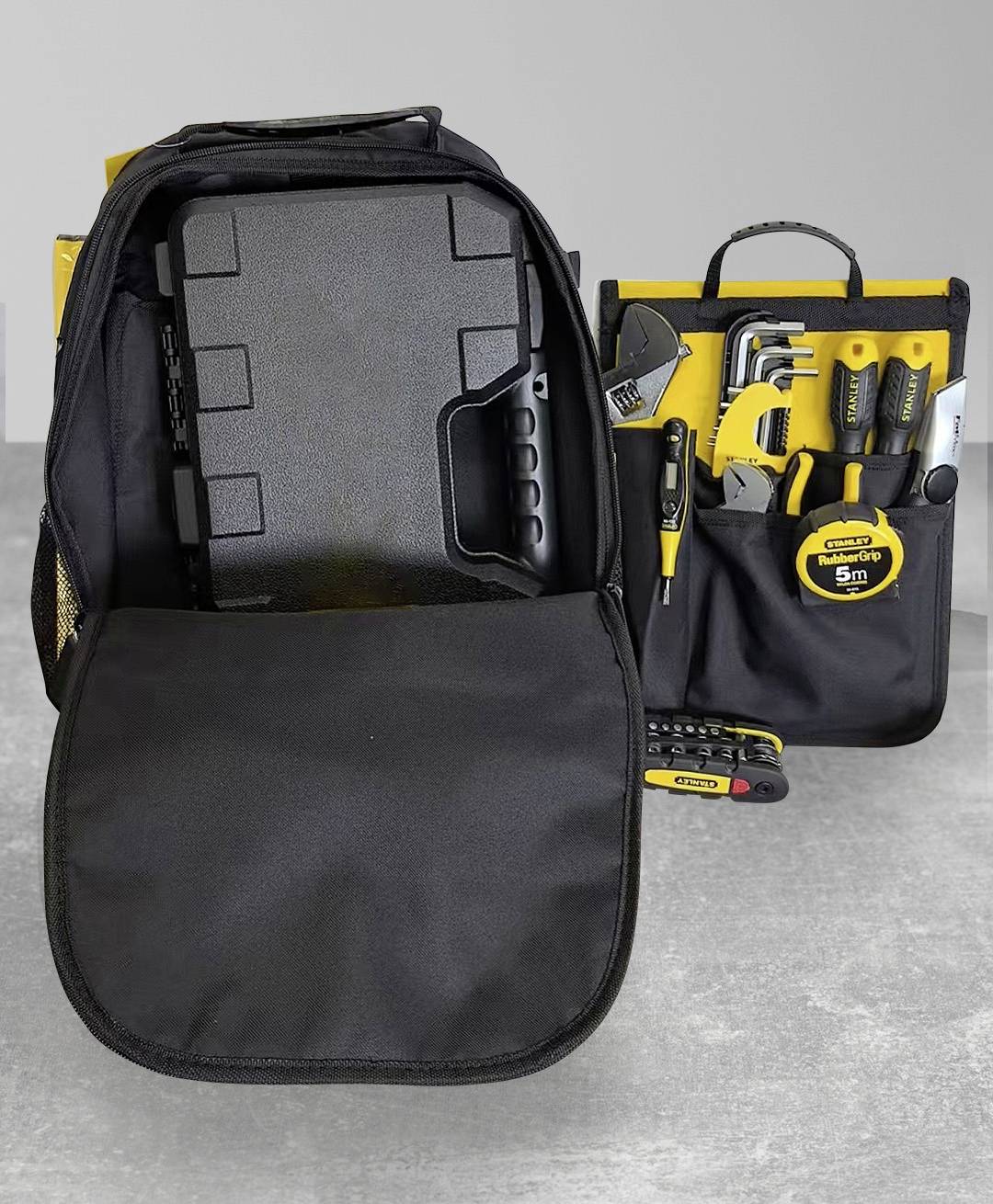 Werkzeug-Rucksack mit einer offenen Klappe, die einen Satz von Werkzeugen einschließlich Zange, Hammer, Schraubendreher und Maßband auf einer grauen Oberfläche zeigt.