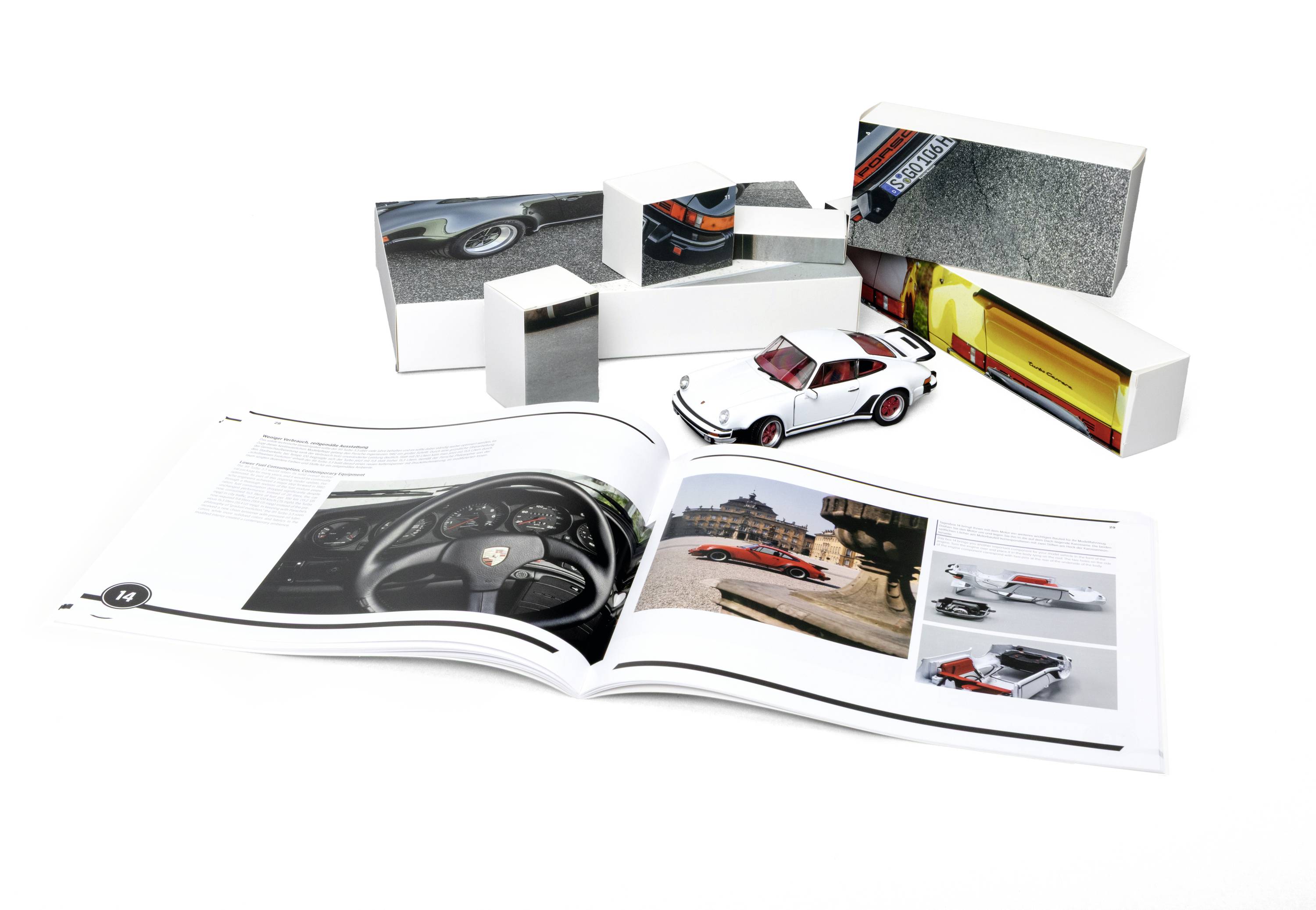 Ein aufgeschlagenes Buch, das Bilder und Text über Porsche zeigt, mit einem Modellauto und gestapelten Büchern im Hintergrund.