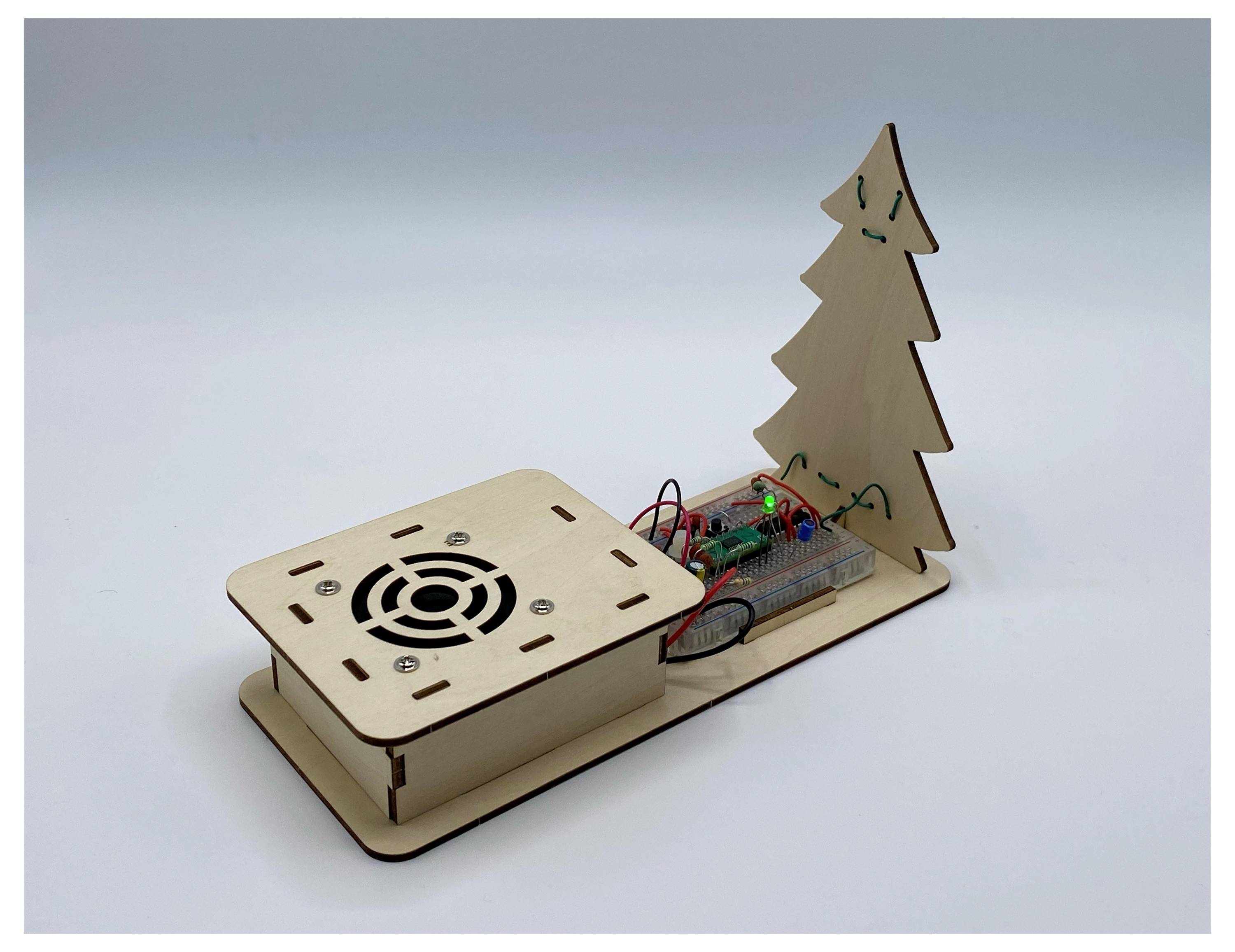 Eine Holzbasis mit einem Ventilator, elektronischen Komponenten und einem Kiefernbaum-Ausschnitt, möglicherweise ein DIY-Projekt oder eine kleine elektronische Anordnung.