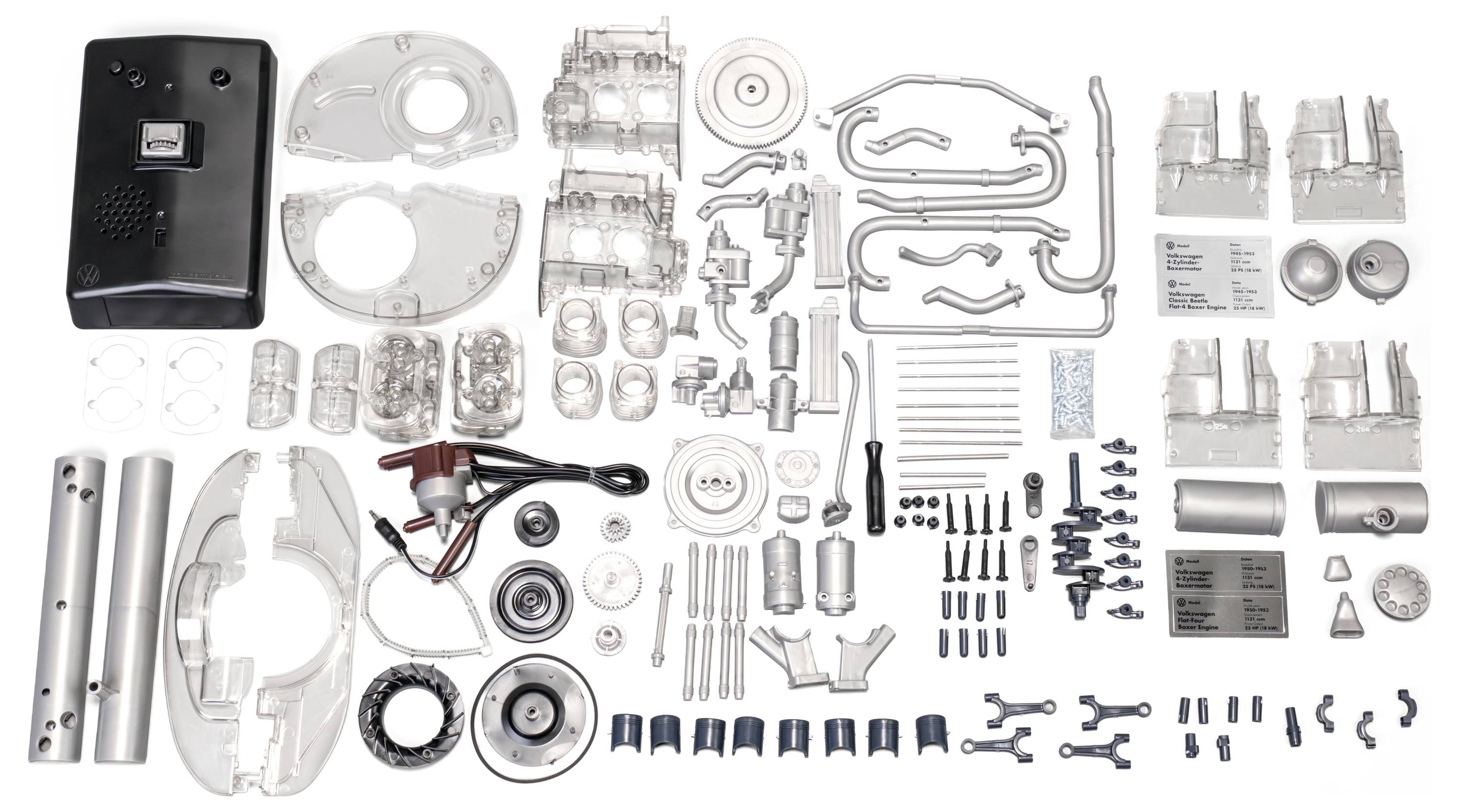 Verschiedene mechanische Komponenten auf einer weißen Oberfläche angeordnet, darunter Metallplatten, Zahnräder, Schrauben und zylindrische Teile, die eine Montagebereitschaft andeuten.
