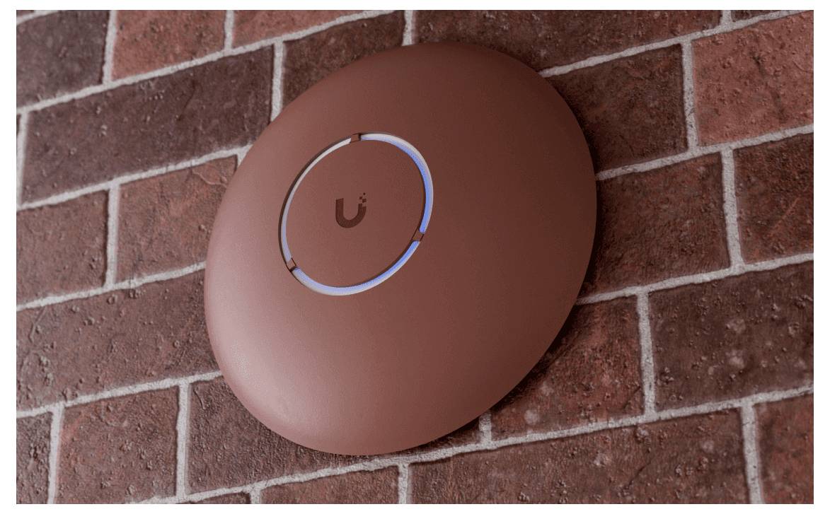 Ein kreisförmiger WLAN-Zugangspunkt ist an einer roten Ziegelwand montiert. In seiner Mitte befindet sich eine leuchtend blaue LED-Anzeige.