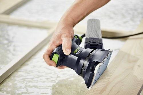 Eine Hand, die einen Exzenterschleifer verwendet, um eine Holzoberfläche zu glätten, wobei der Staub in einem angeschlossenen Beutel aufgefangen wird.