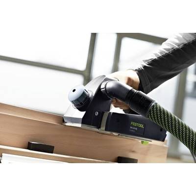 Eine Person verwendet einen Festool-Handhobel, um die Kante eines Holzbretts im Innenbereich zu glätten.