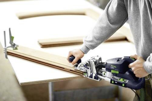 Eine Person verwendet ein Zimmermannswerkzeug, um Holzbretter auf einer Werkbank zu verbinden.