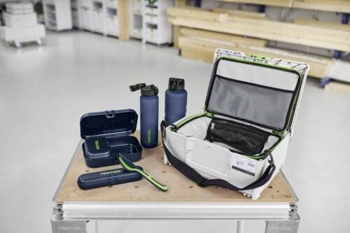 Brotdose, Flaschen und Lunch-Tasche mit 'FESTOOL' Logo auf einer Werkbank, Werkstattumgebung mit Holzbalken und Stauraum im Hintergrund.