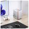 Ein minimalistischer Arbeitsplatz mit einem kompakten, silbernen Desktop-Computer neben einem Monitor, mit einem weißen Gaming-Controller und einer Tastatur auf einem Holzschreibtisch.