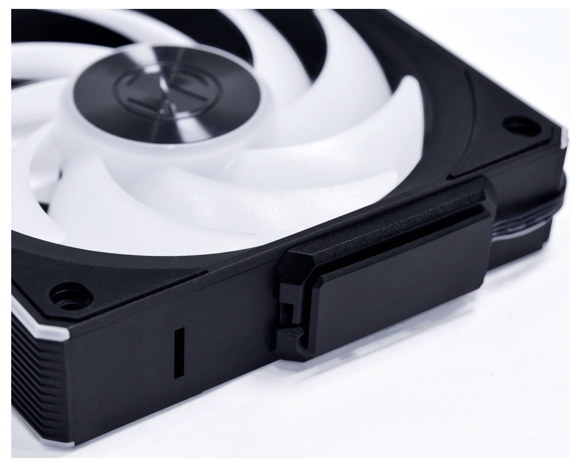 Ein schwarzer und weißer Computer-Kühlventilator mit sichtbaren Klingen und einem zentralen Nabe, der auf einer flachen Oberfläche ruht.