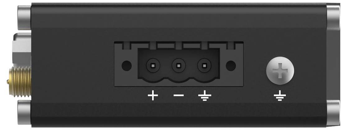 Ein schwarzes elektronisches Gerät mit drei Anschlüssen, die mit '+', '-' und Masse beschriftet sind, zusammen mit einer Schraube zur Sicherung der Verbindung.