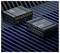 Zwei elektronische Geräte, die auf einer schwarz-blauen gestreiften Oberfläche platziert sind, zeigen mehrere Eingabe- und Ausgabeports, beschriftet mit „RUTX12" und „RUTX52".
