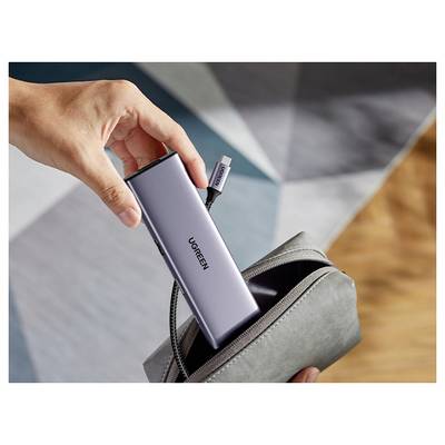 Eine Hand legt einen UGREEN USB-C-Hub in einen kleinen grauen Beutel und deutet damit auf Mobilität und Praktikabilität für Technikzubehör hin.