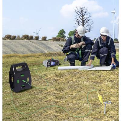 Zwei Arbeiter in Sicherheitsausrüstung prüfen Baupläne im Freien in der Nähe von Windturbinen, wobei elektrische Ausrüstung auf dem Gras auf ein Projekt im Bereich erneuerbarer Energien hindeutet.
