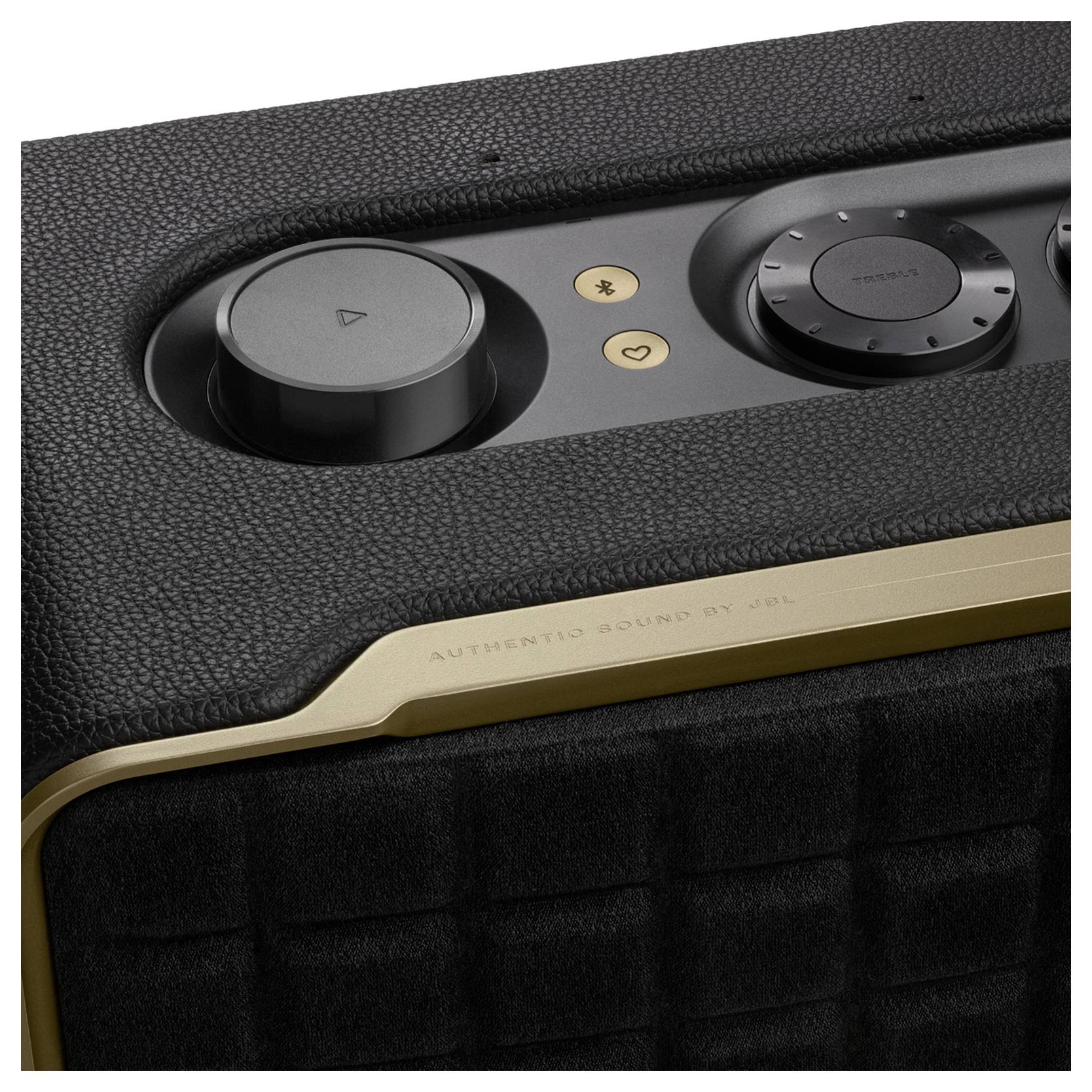 Eine Nahaufnahme eines schwarzen texturierten Lautsprechers mit Kontrollreglern und Tasten auf der Oberseite, mit einem goldenen Akzent und dem Text „Authentischer Sound von".