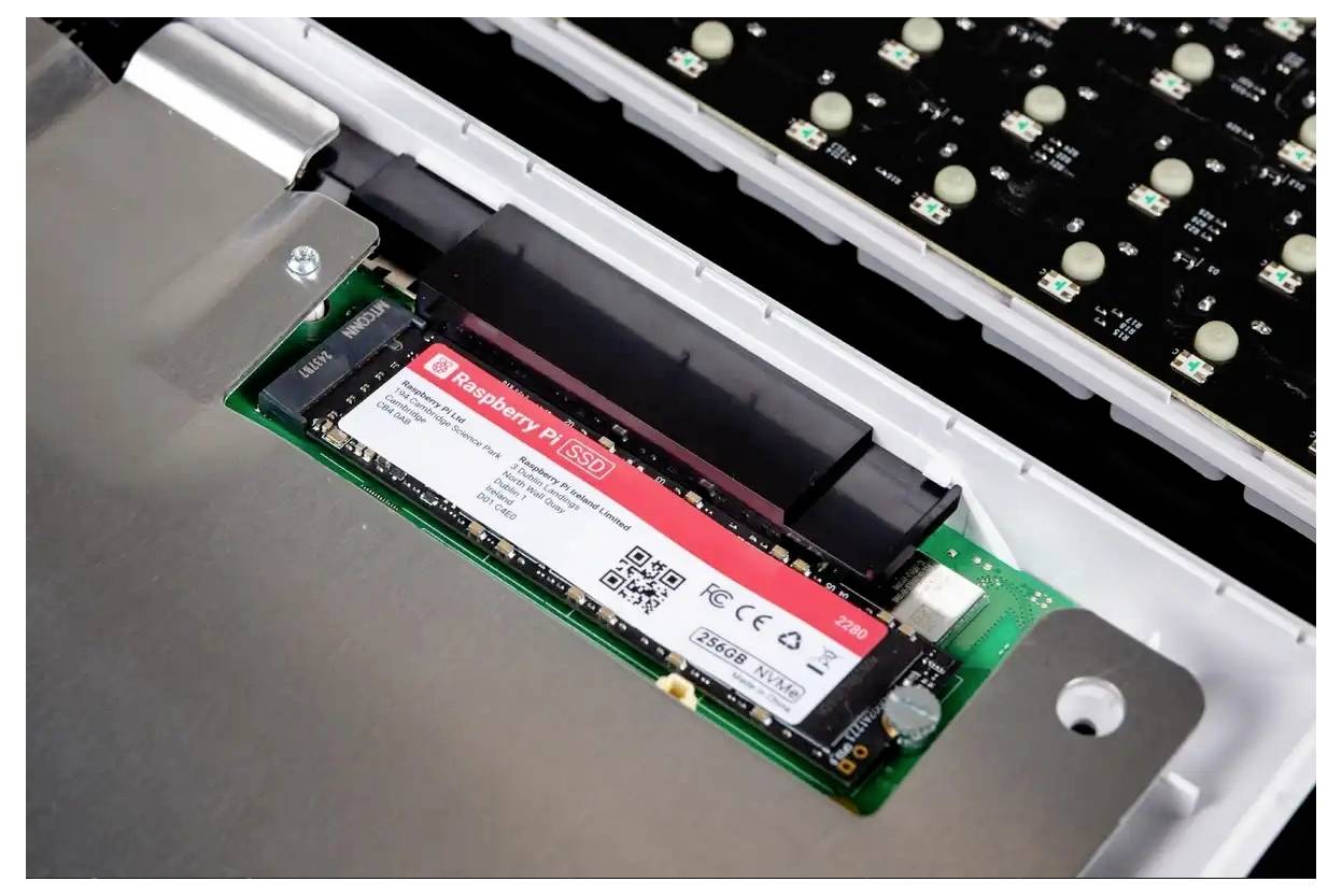 Ein Nahaufnahmefoto einer geöffneten Tastatur, die eine eingelegte Raspberry Pi SSD zeigt, die mit einer grünen Leiterplatte verbunden ist und deren Anschlüsse und Beschriftungen sichtbar sind.