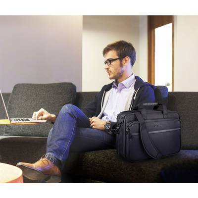 Ein Mann sitzt auf einer Couch und benutzt einen Laptop, neben ihm liegt eine schwarze Laptoptasche.