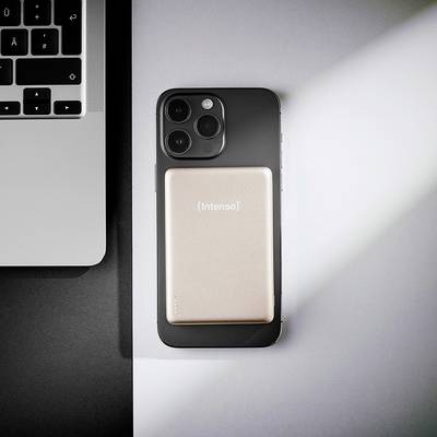 Ein Smartphone mit Triple-Kamera-Setup liegt neben der Tastatur eines Laptops auf einem Schreibtisch. Eine Powerbank mit der Aufschrift "Intenso" ruht auf dem Telefon.