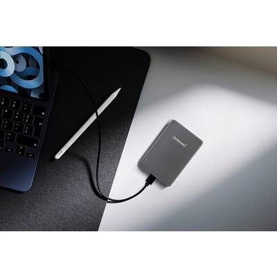 Ein Laptop, der an einer externen Festplatte auf einem Schreibtisch angeschlossen ist, mit einem Stylus in der Nähe, was eine technische Arbeitsplatz-Einrichtung andeutet.
