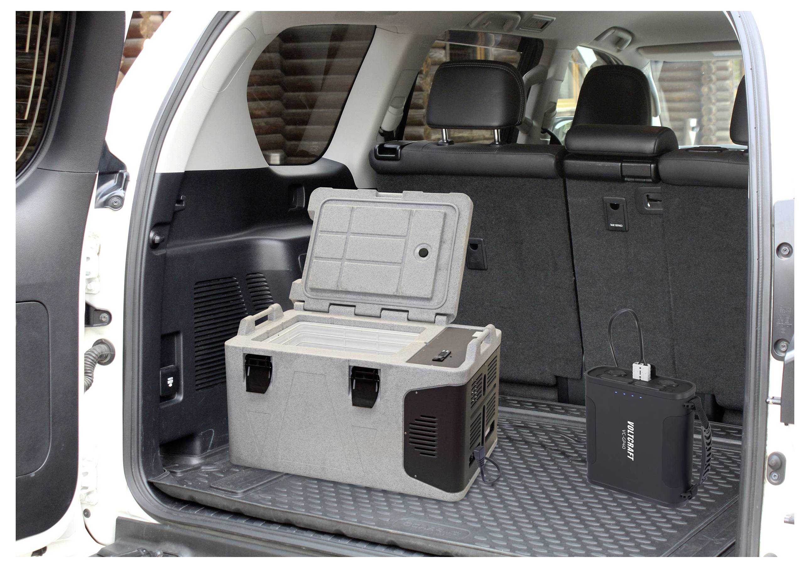 „Kühlbox im Kofferraum des Fahrzeugs mit geöffnetem Deckel neben einer tragbaren Stromstation, die praktische Reisespeicherung und eine Stromlösung veranschaulicht."