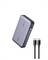 Eine silberne tragbare Powerbank mit einer digitalen Anzeige, die den Batteriestand auf der Seite zeigt, und zwei schwarzen USB-C-Kabeln, die daneben liegen.